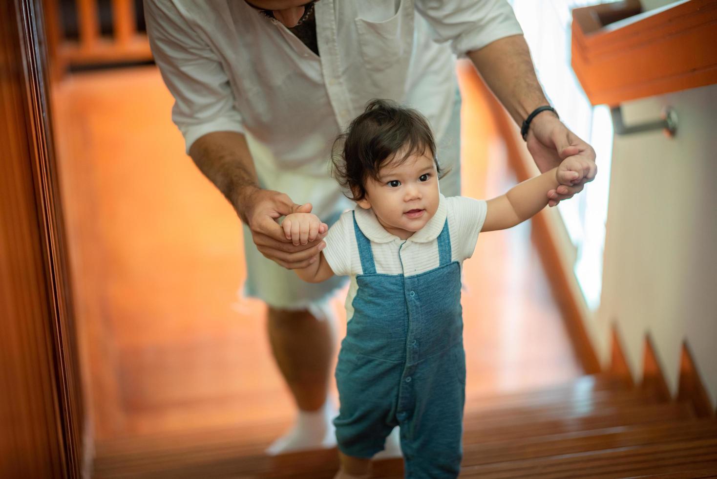 lindo concepto de familia de niño pequeño, bebé aprendiendo a caminar con el padre y la madre para ayudar a cuidar y tomar la mano, primer paso con el apoyo de los padres de la infancia, pequeño retrato de amor niño pequeño en casa foto