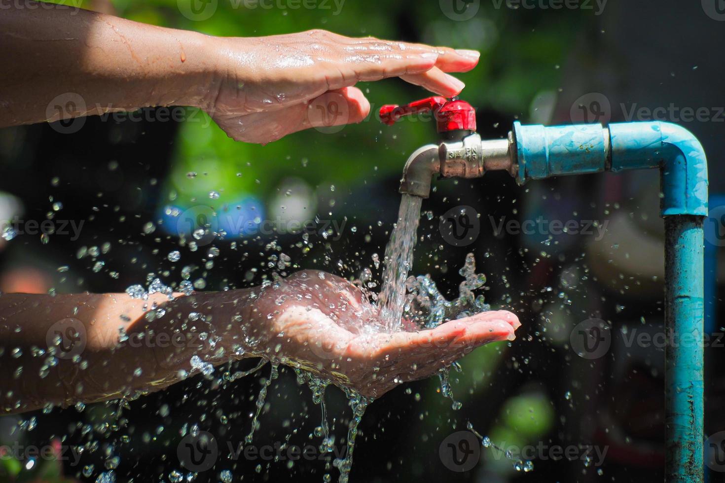 Water concept in everyday life. Hands supporting the water flowing from the faucet. water splashing from the tap photo