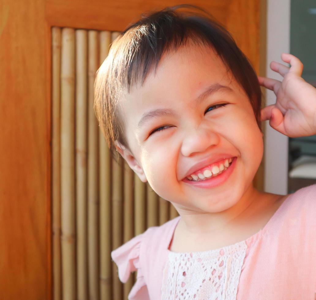 niña asiática, niña pequeña con adorable cabello corto sonriendo en casa. foto