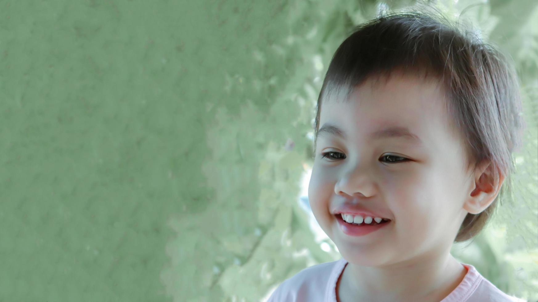 Captura de pantalla de una encantadora niña asiática de 3 años mirando a la izquierda. foto