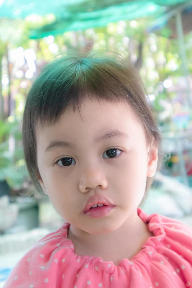 Cute baby Asian girl, little toddler child with adorable short bang hair looking at camera. photo