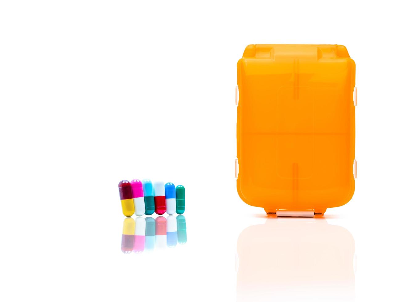 Orange pills box with colorful capsule pills isolated on white background with copy space. Prepare medicine before work or travel abroad concept. photo