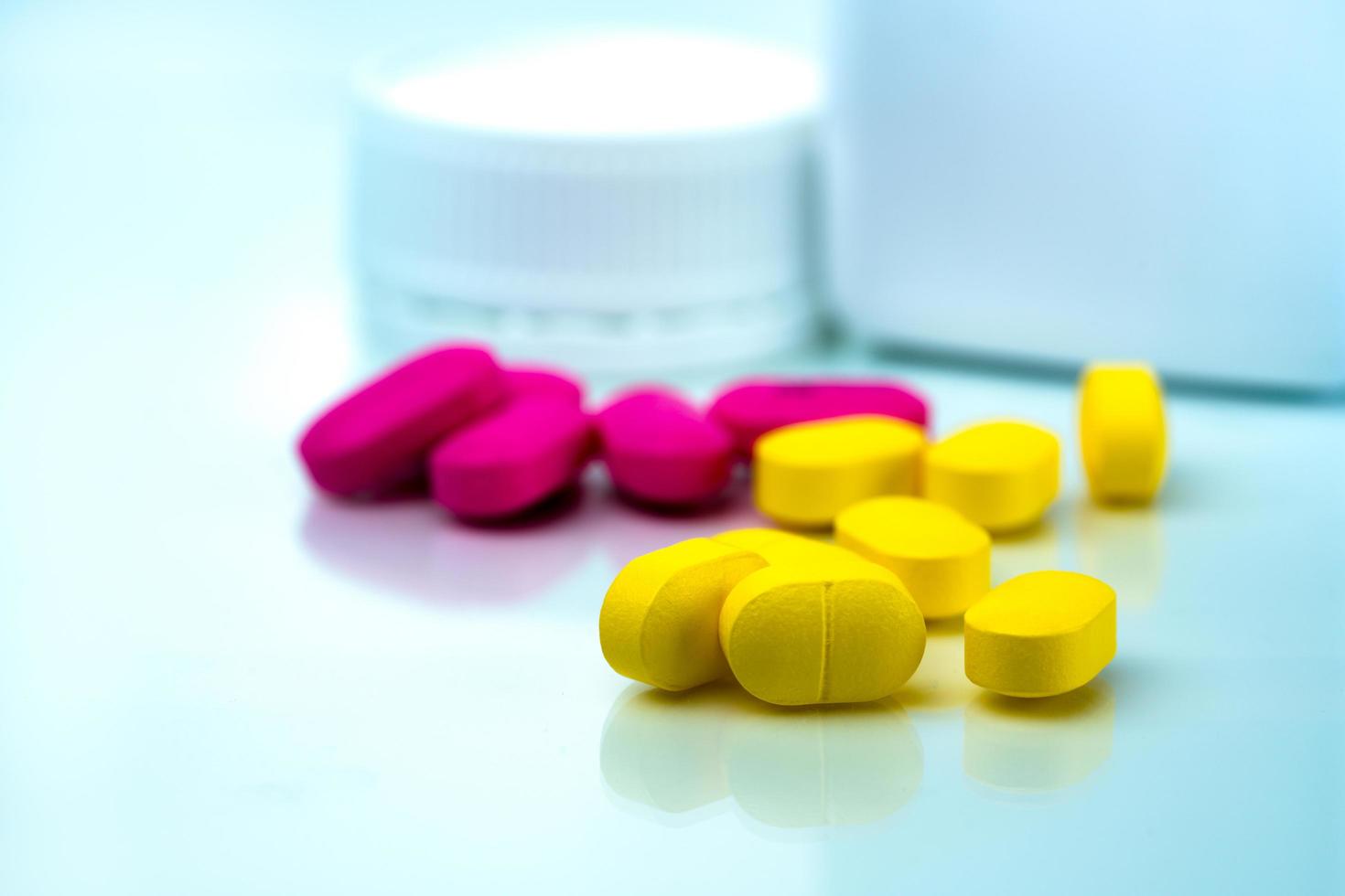 Yellow tablets pills blurred pink tablets and drug bottle. Painkiller. Pharmaceutical industry. Pharmacy drugstore products. Medication use in hospital. Pharmacology. Prescription drugs. Healthcare. photo