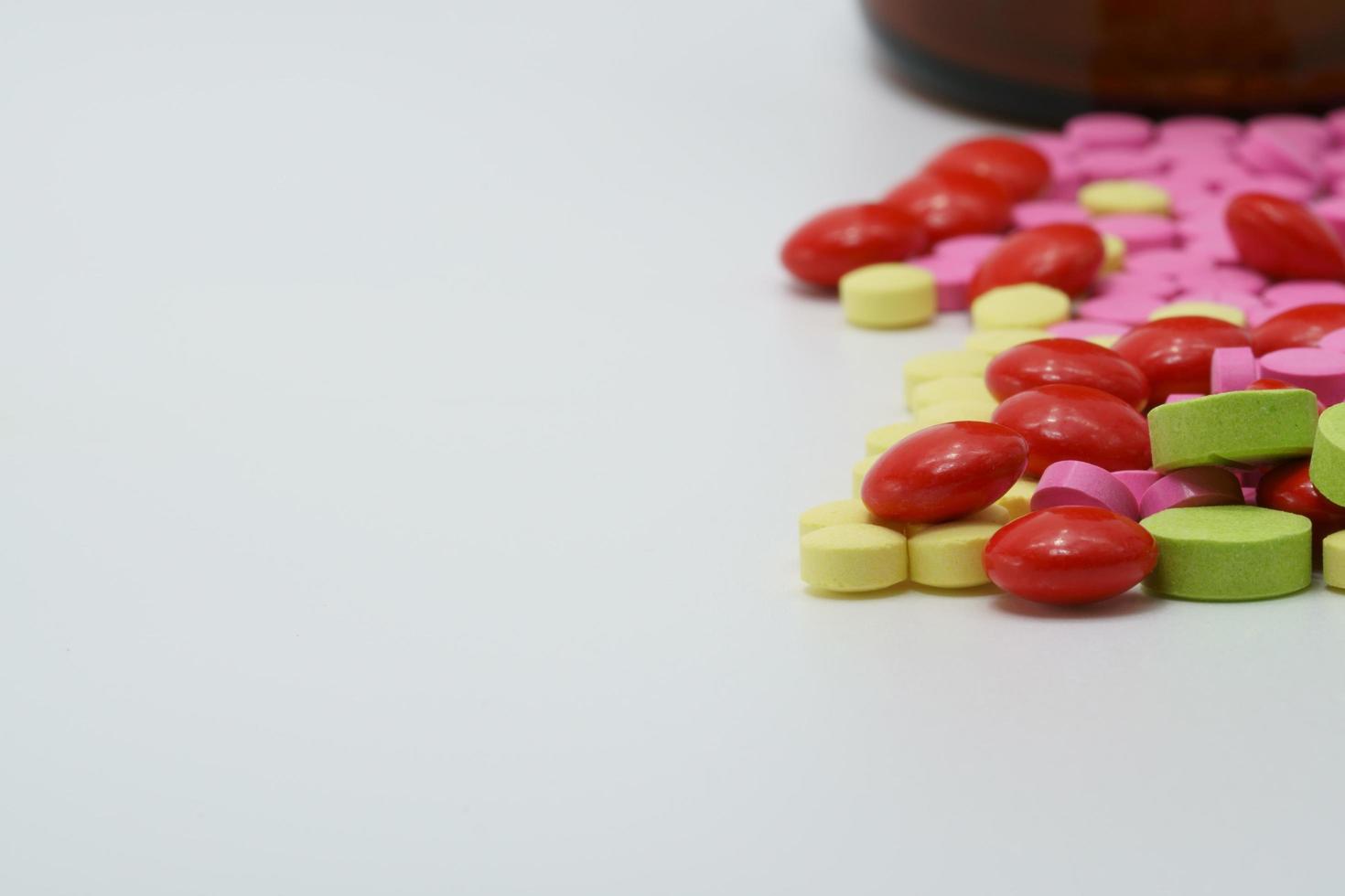 Drug interactions, Colorful round tablets pills on white background. Pharmaceutical product. Pharmacy drugstore. Global healthcare. Vitamin and supplement. Pink, red, green, and yellow tablet pills. photo