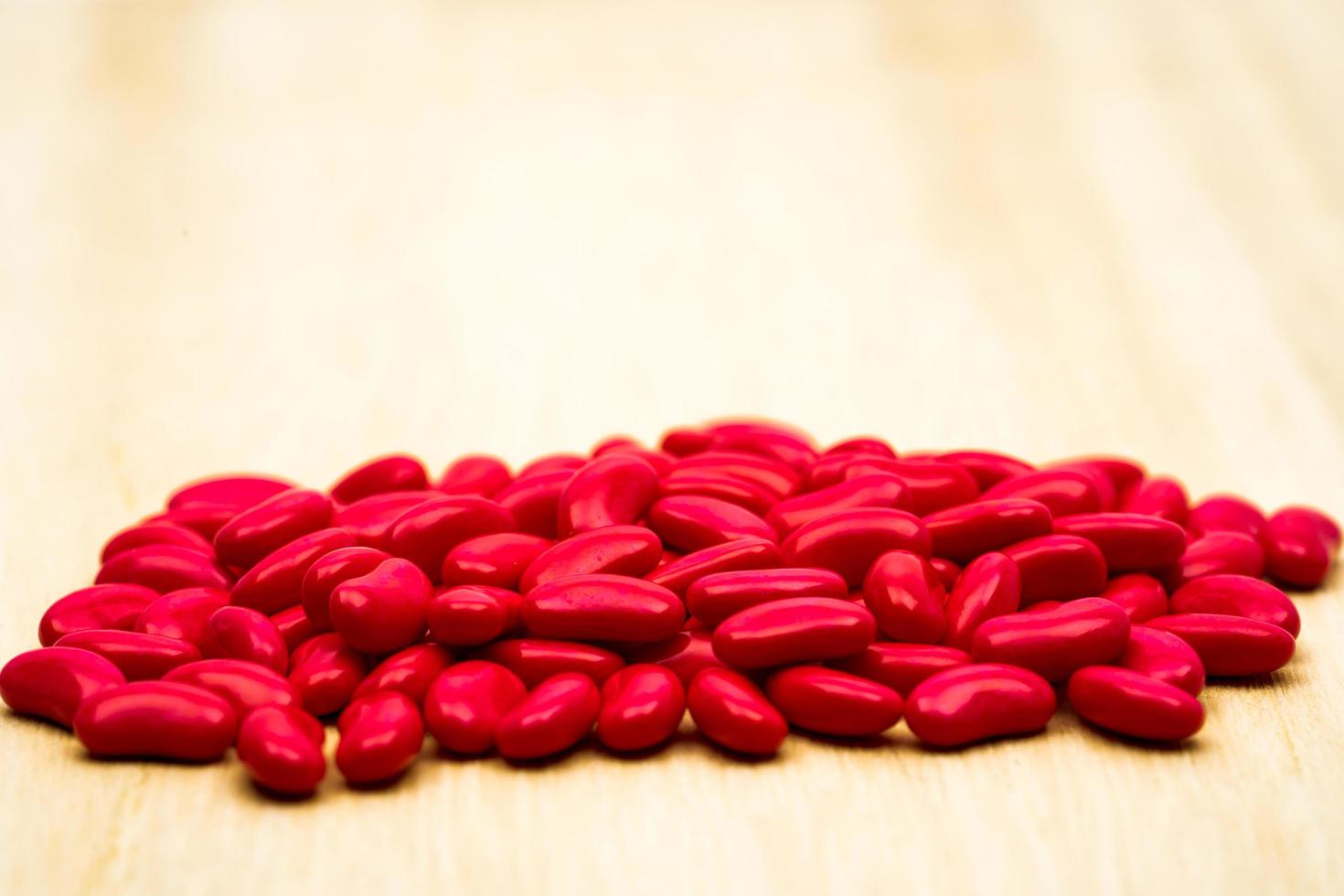Red kidney sugar coated tablets pills on wood table with copy space photo