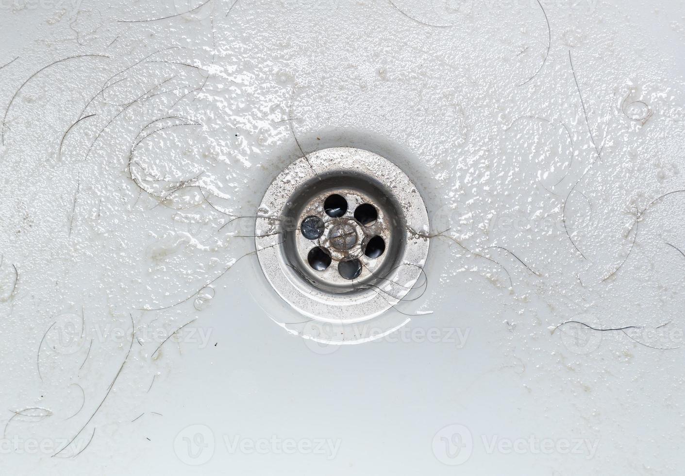 Dirty wash hand basin showing grungy drain with bits of hair photo