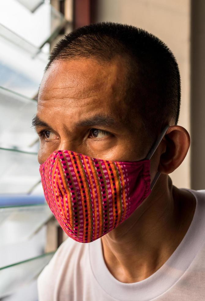 A red cloth mask on the face, looking through the louvers. photo