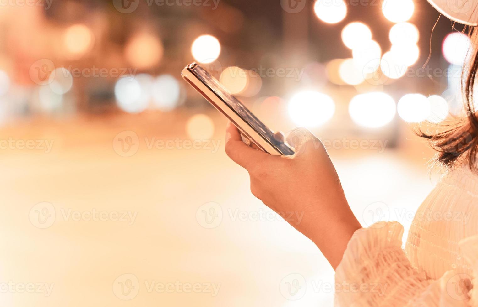 Close-up image of female hand using mobile smartphone at night city street. concept of searching or social networks. photo