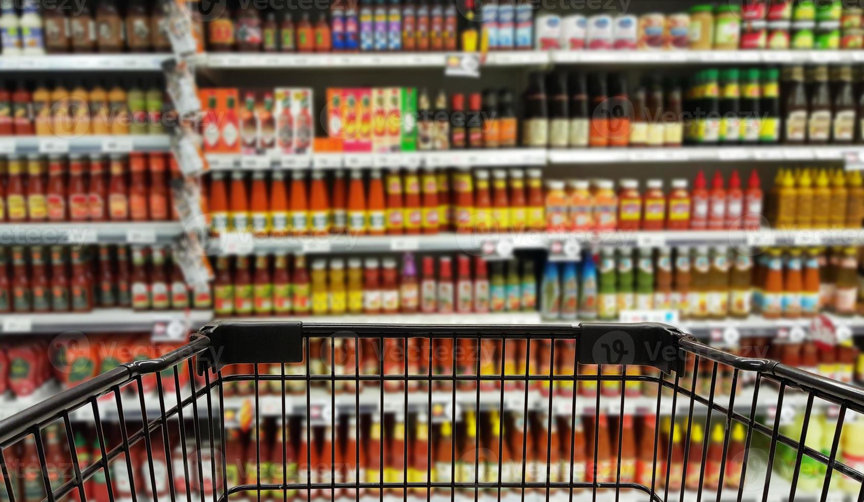 Abstract blurred image of condiments department with trolley, selective focused at shopping cart. photo