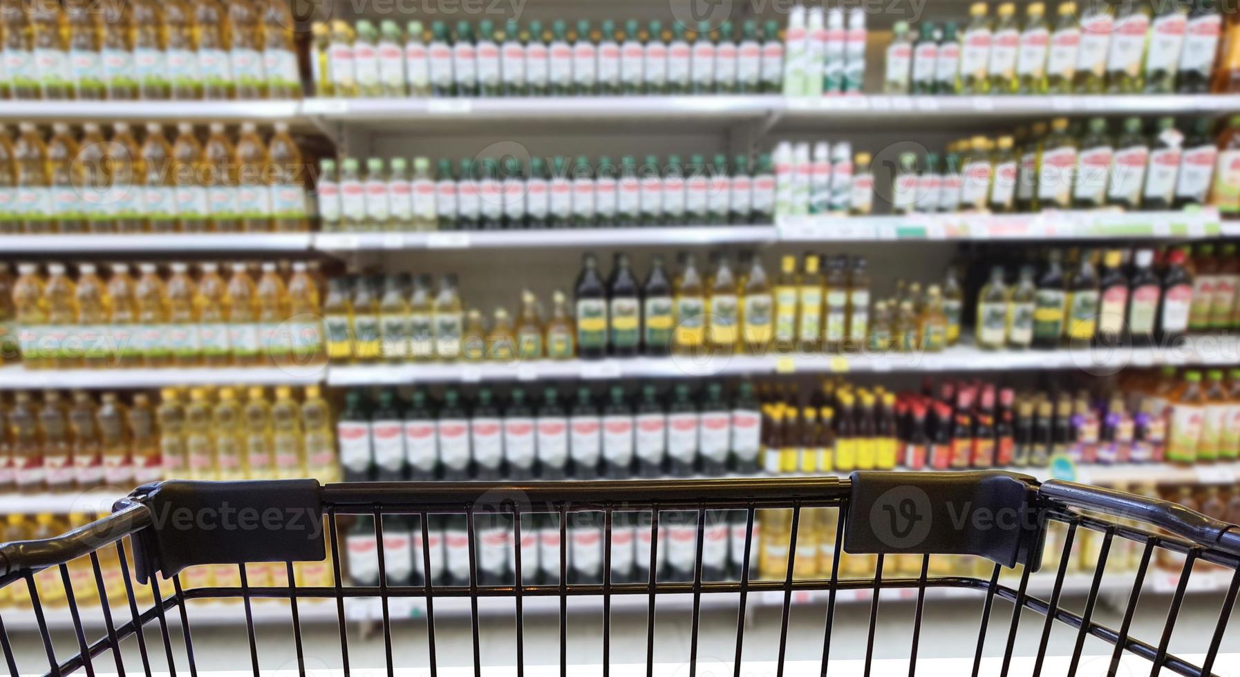 imagen borrosa abstracta de botellas de aceite vegetal para cocinar en grandes almacenes, selectiva enfocada en el carro de la compra. foto