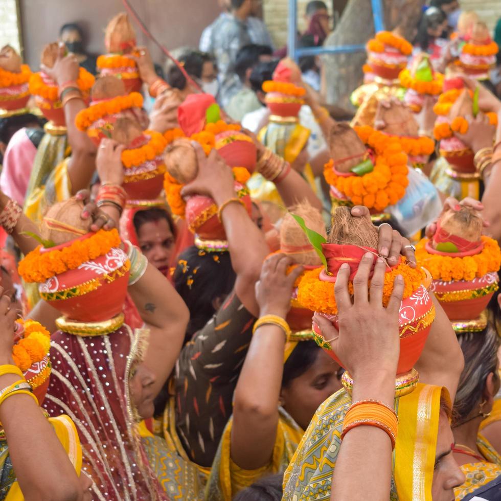 New Delhi, India April 03 2022 - Women with Kalash on head during Jagannath Temple Mangal Kalash Yatra, Indian Hindu devotees carry earthen pots containing sacred water with a coconut on top photo