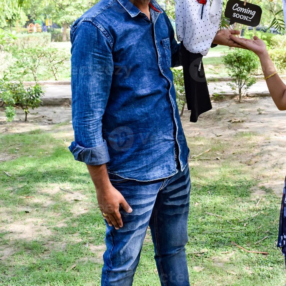Indian couple posing for maternity baby shoot. The couple is posing in a lawn with green grass and the woman is falunting her baby bump in Lodhi Garden in New Delhi, India photo
