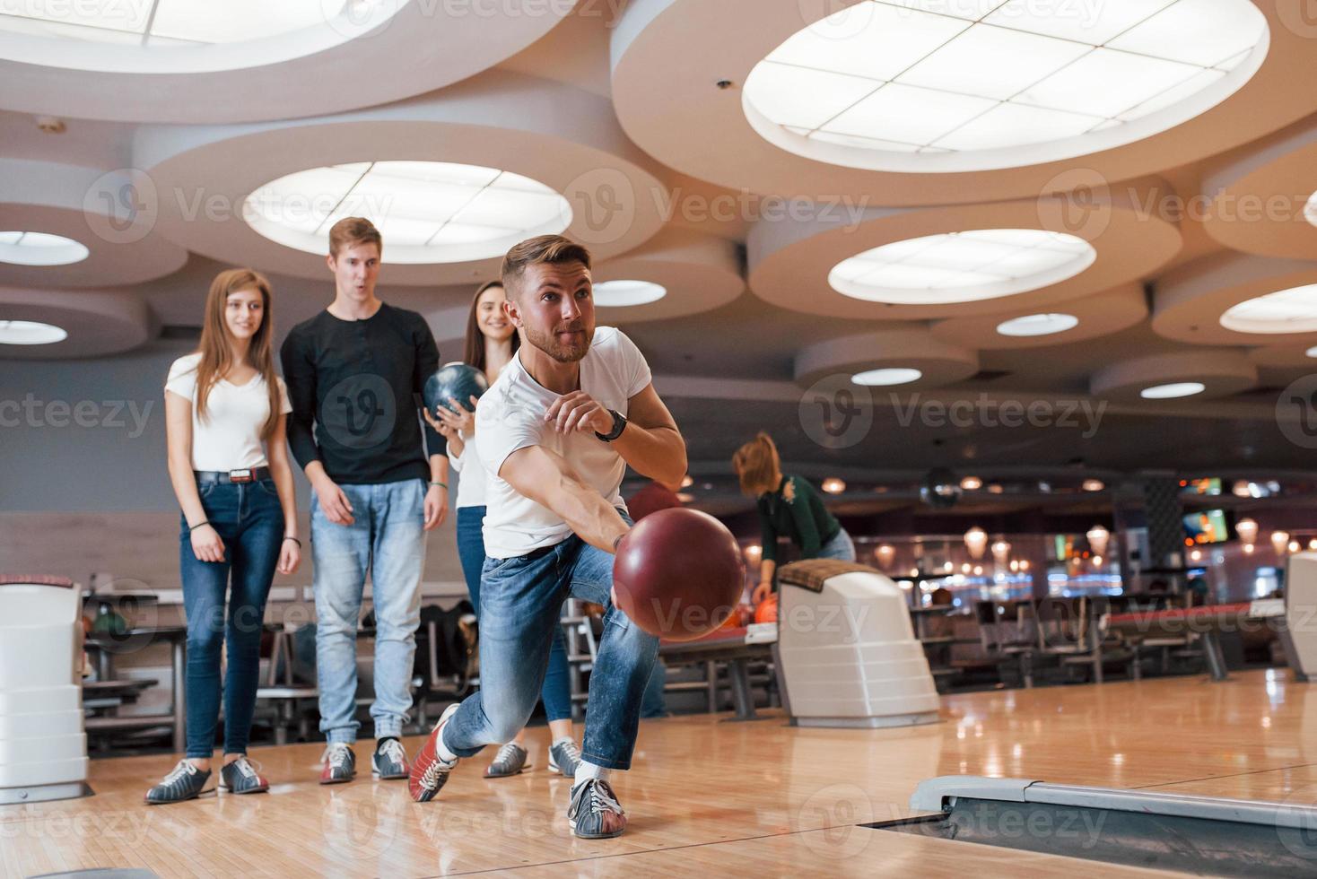 pelota casi volando. jóvenes amigos alegres se divierten en el club de bolos los fines de semana foto