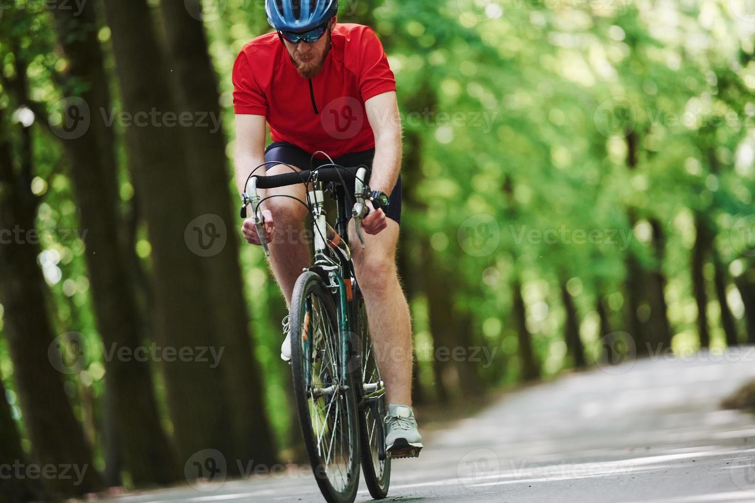 Fitness day. Cyclist on a bike is on the asphalt road in the forest photo