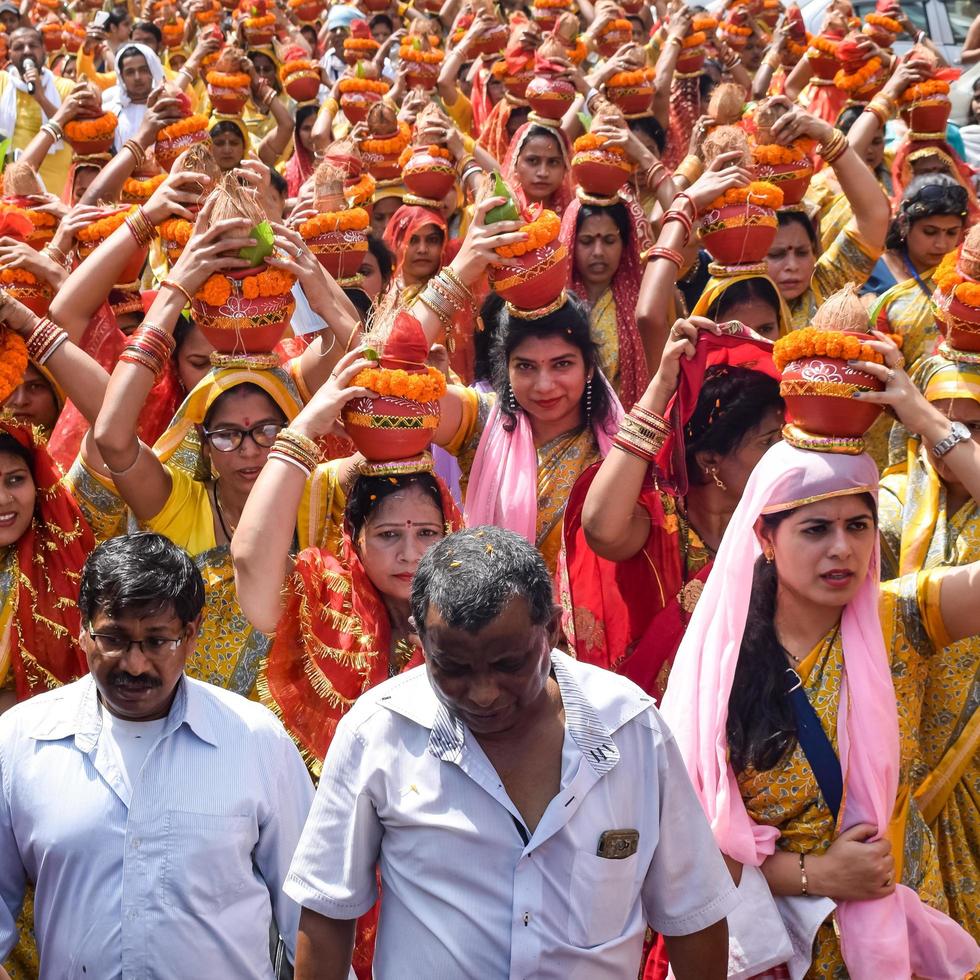 New Delhi, India April 03 2022 - Women with Kalash on head during Jagannath Temple Mangal Kalash Yatra, Indian Hindu devotees carry earthen pots containing sacred water with a coconut on top photo