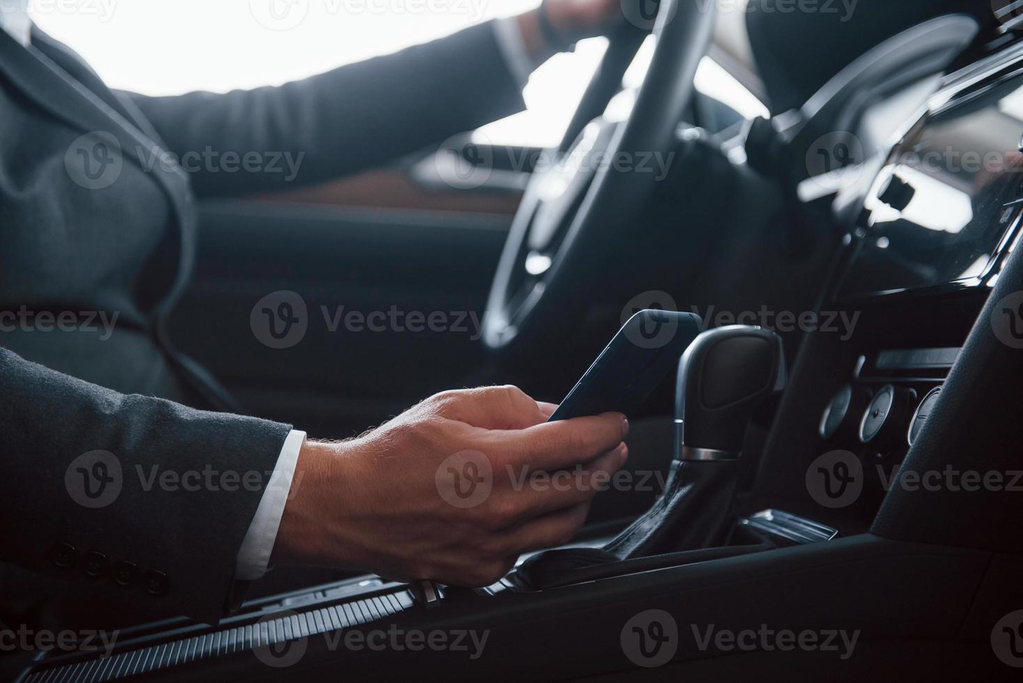 no use el teléfono y la unidad. hombre de negocios moderno probando su auto nuevo en el salón del automóvil foto