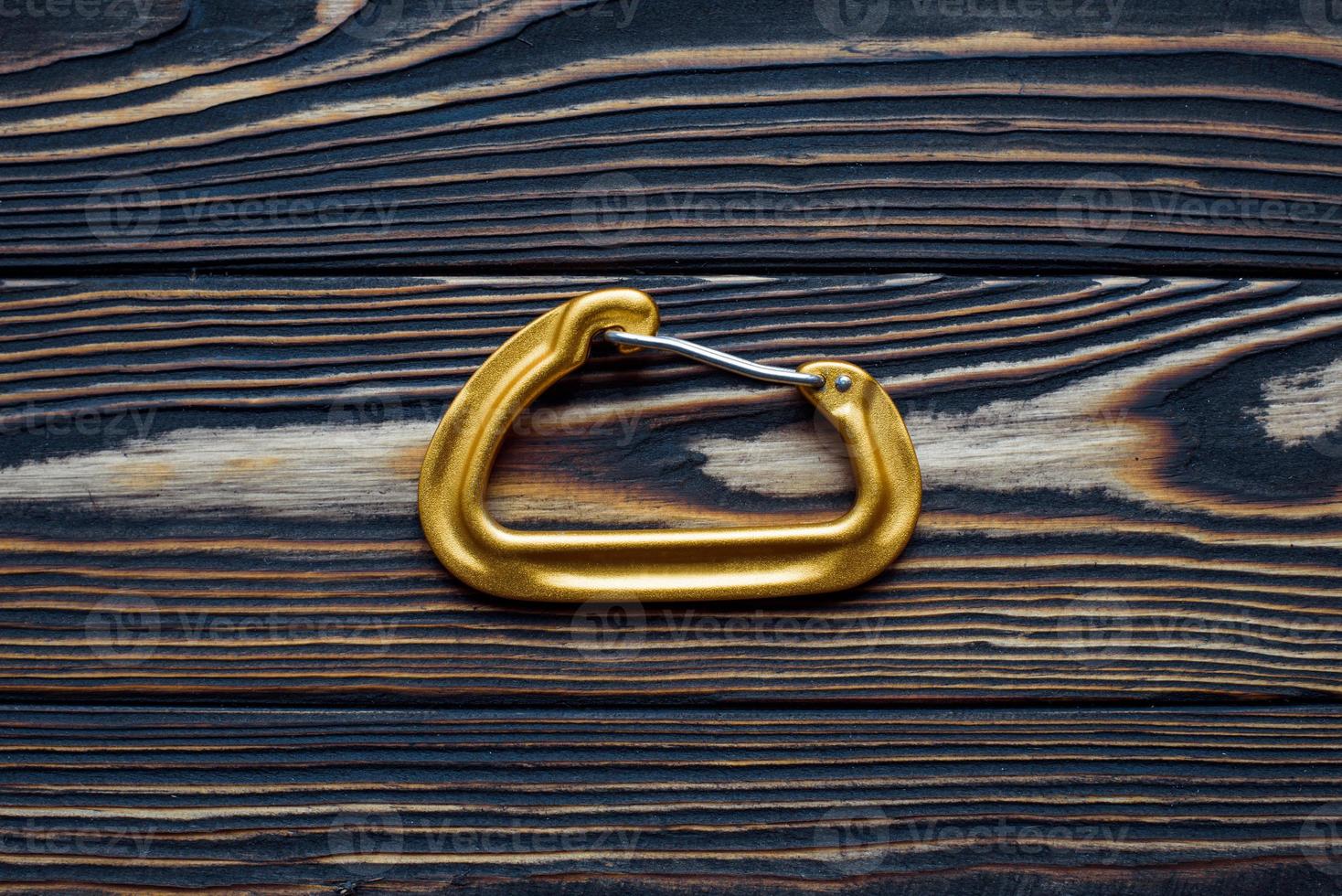 Close up view. Isolated photo of climbing equipment. Part of carabiner lying on the wooden table