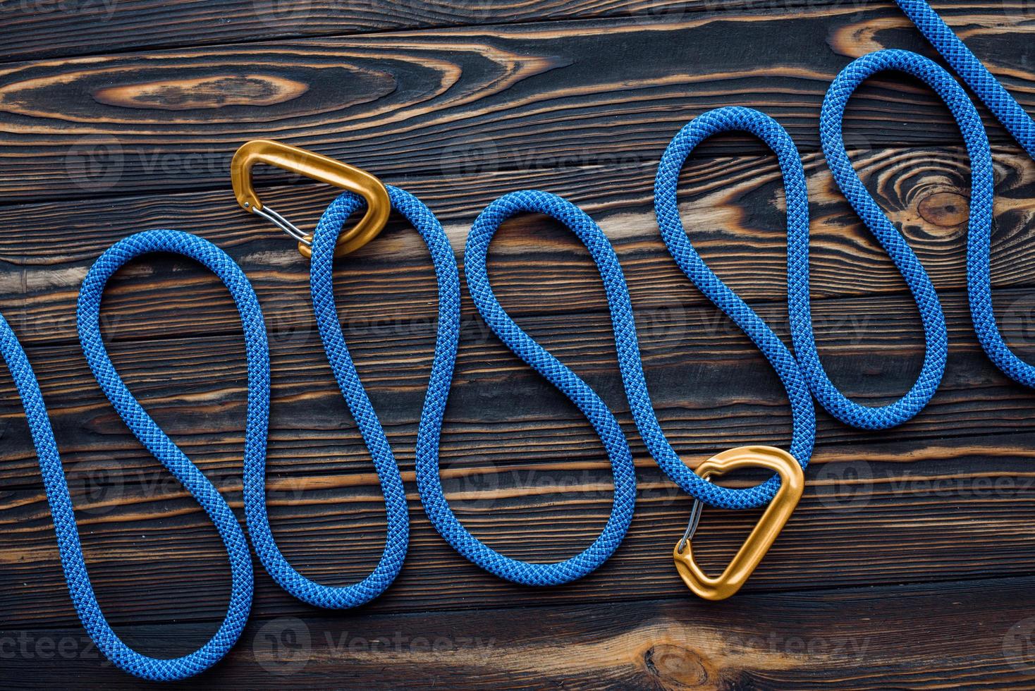 Long blue knot. Isolated photo of climbing equipment. Parts of carabiners lying on the wooden table