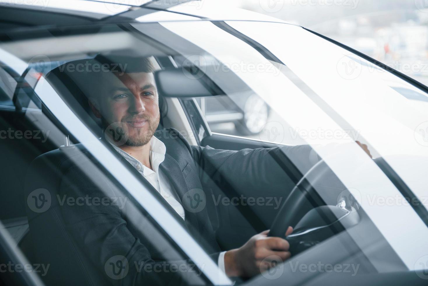 dónde ir. hombre de negocios moderno probando su auto nuevo en el salón del automóvil foto