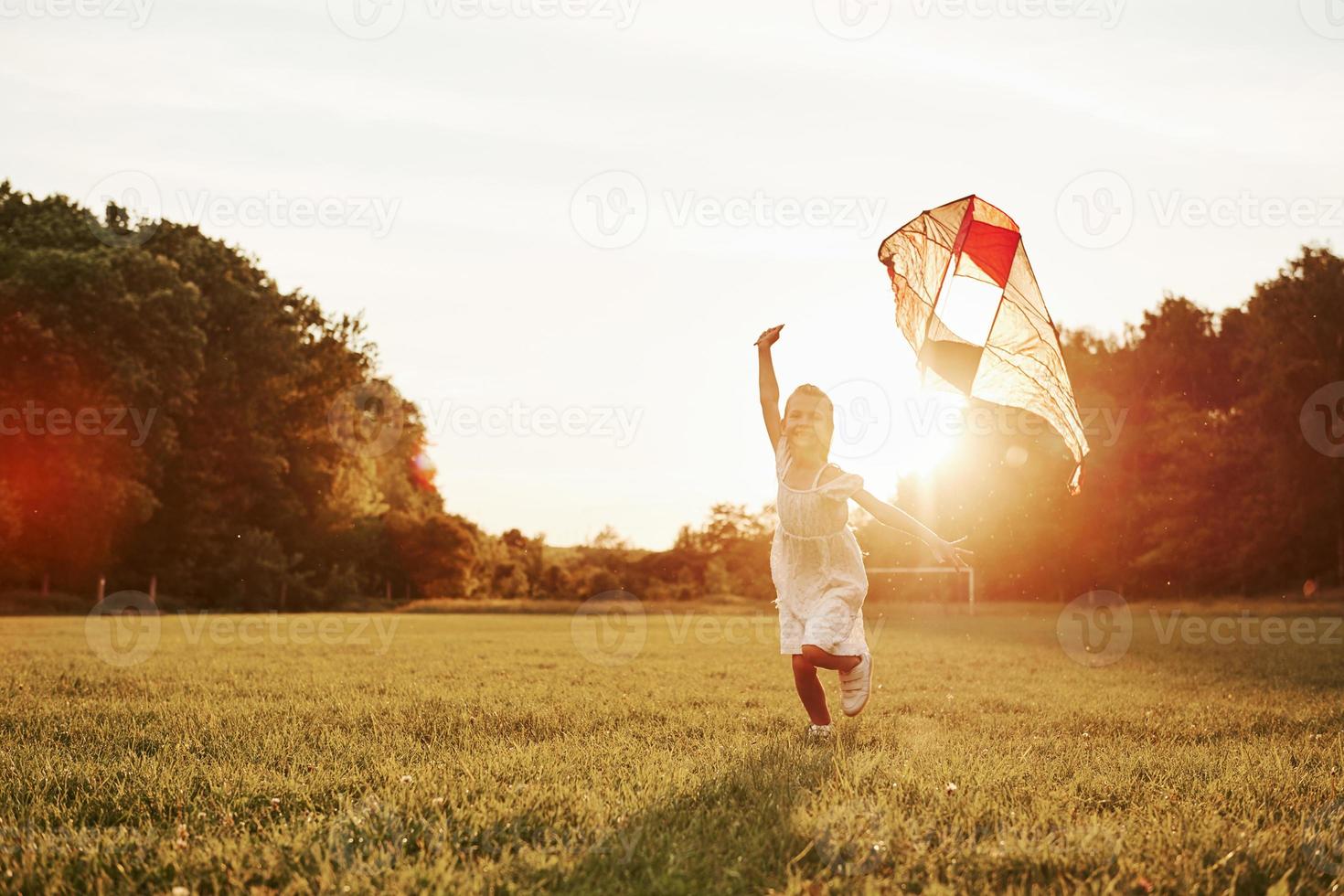 chico positivo. chica feliz vestida de blanco diviértete con cometa en el campo. Hermosa naturaleza foto
