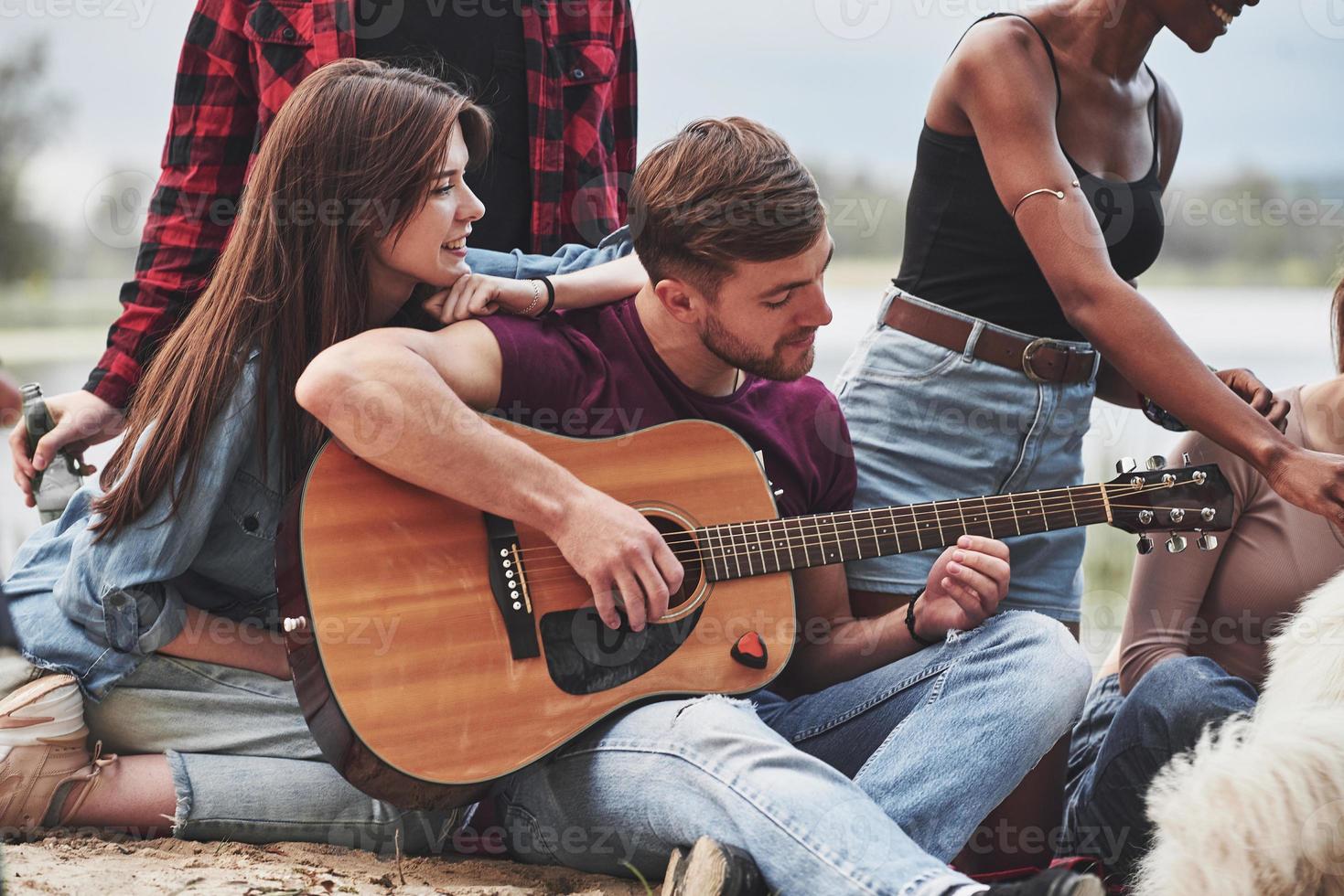 Concentrated at playing. Group of people have picnic on the beach. Friends have fun at weekend time photo