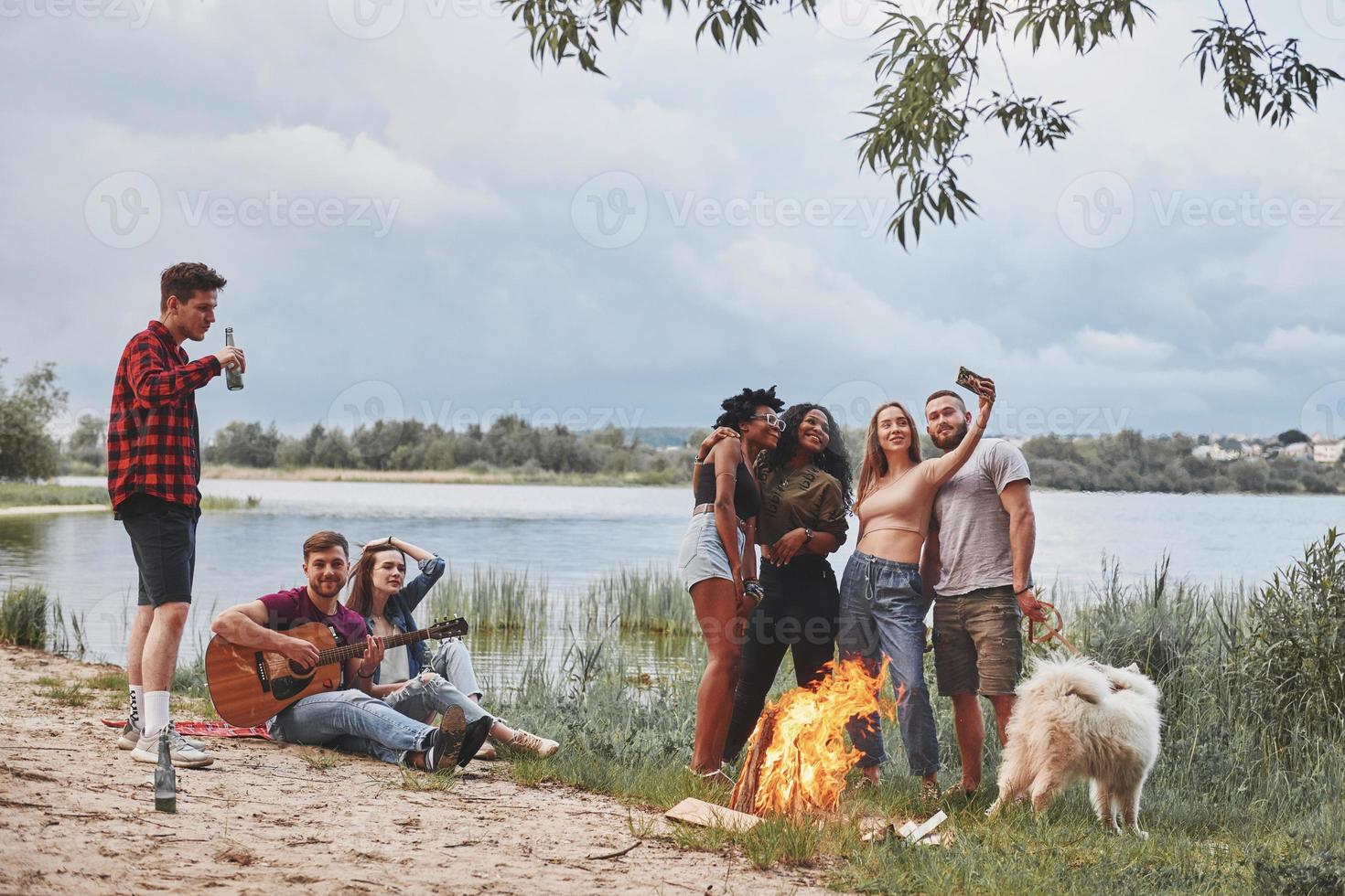 Capture the moment. Group of people have picnic on the beach. Friends have fun at weekend time photo