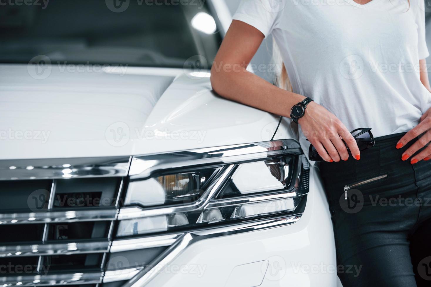 Man leaning on vehicle. Particle view of modern luxury white car parked indoors at daytime photo