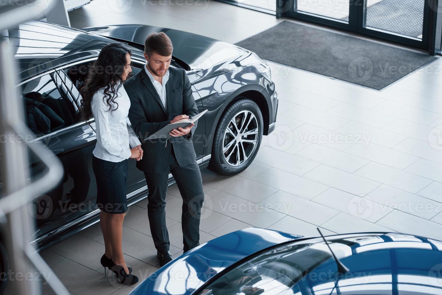 vista aérea. Cliente femenino y moderno y elegante hombre de negocios barbudo en el salón del automóvil foto