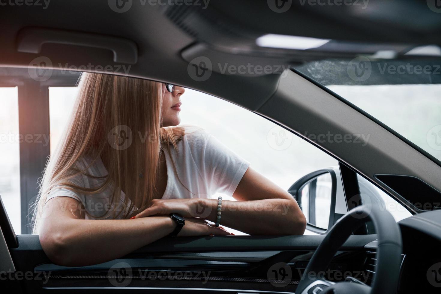 Girl and modern car in the salon. At daytime indoors. Buying new vehicle photo