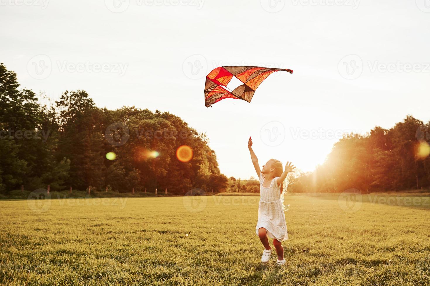 Happy childhood. Happy girl in white clothes have fun with kite in the field. Beautiful nature photo