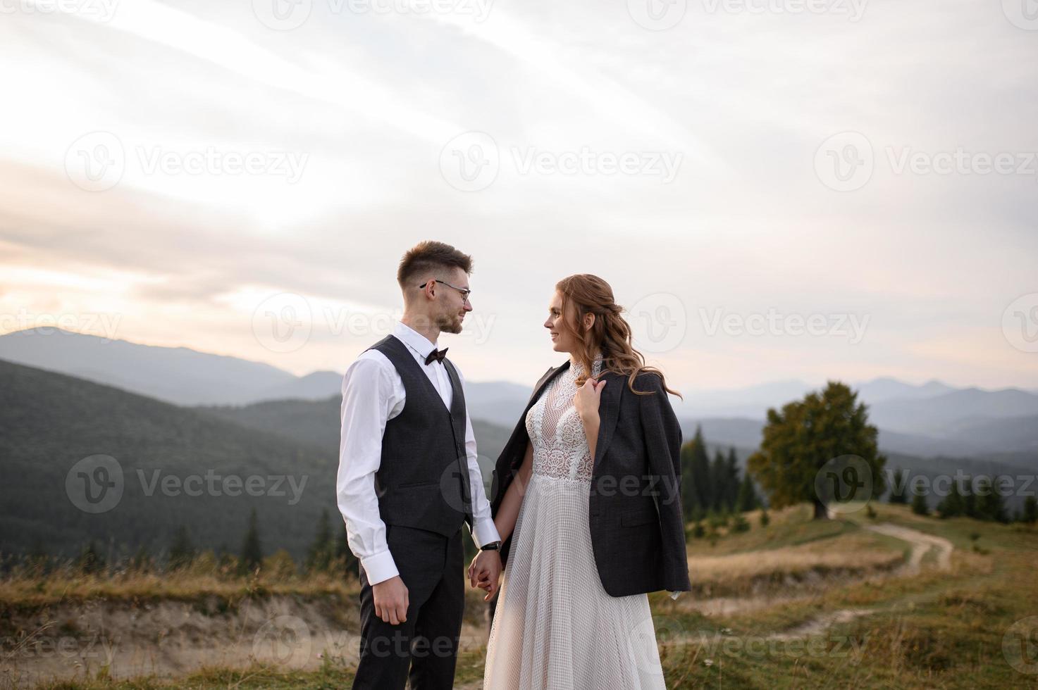 happy stylish bride and groom running and having fun in mountains on summer sunny day photo