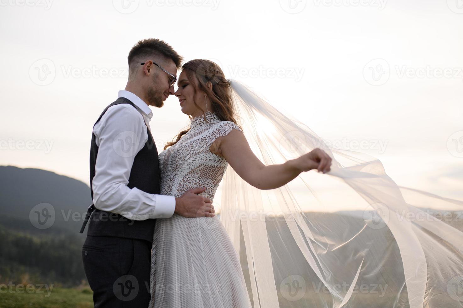 happy stylish bride and groom running and having fun in mountains on summer sunny day photo