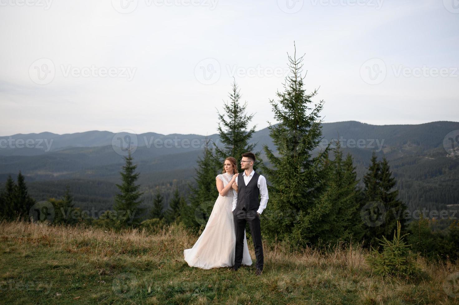 happy stylish bride and groom running and having fun in mountains on summer sunny day photo