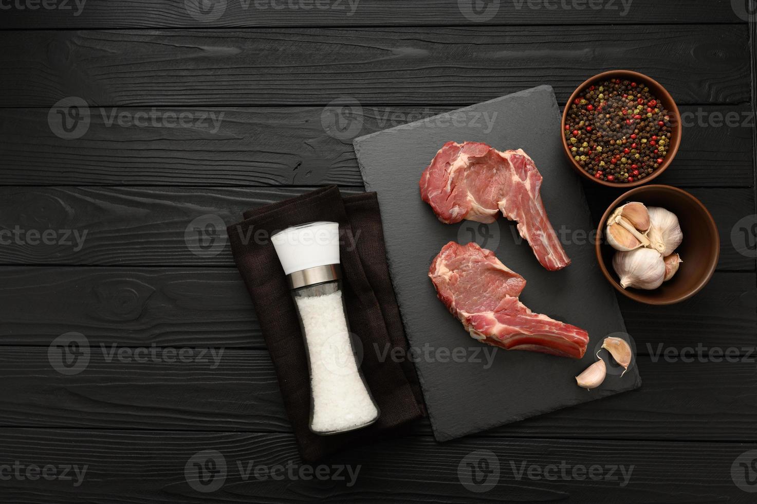 Raw cowboy steak and spices on a black wooden background. photo