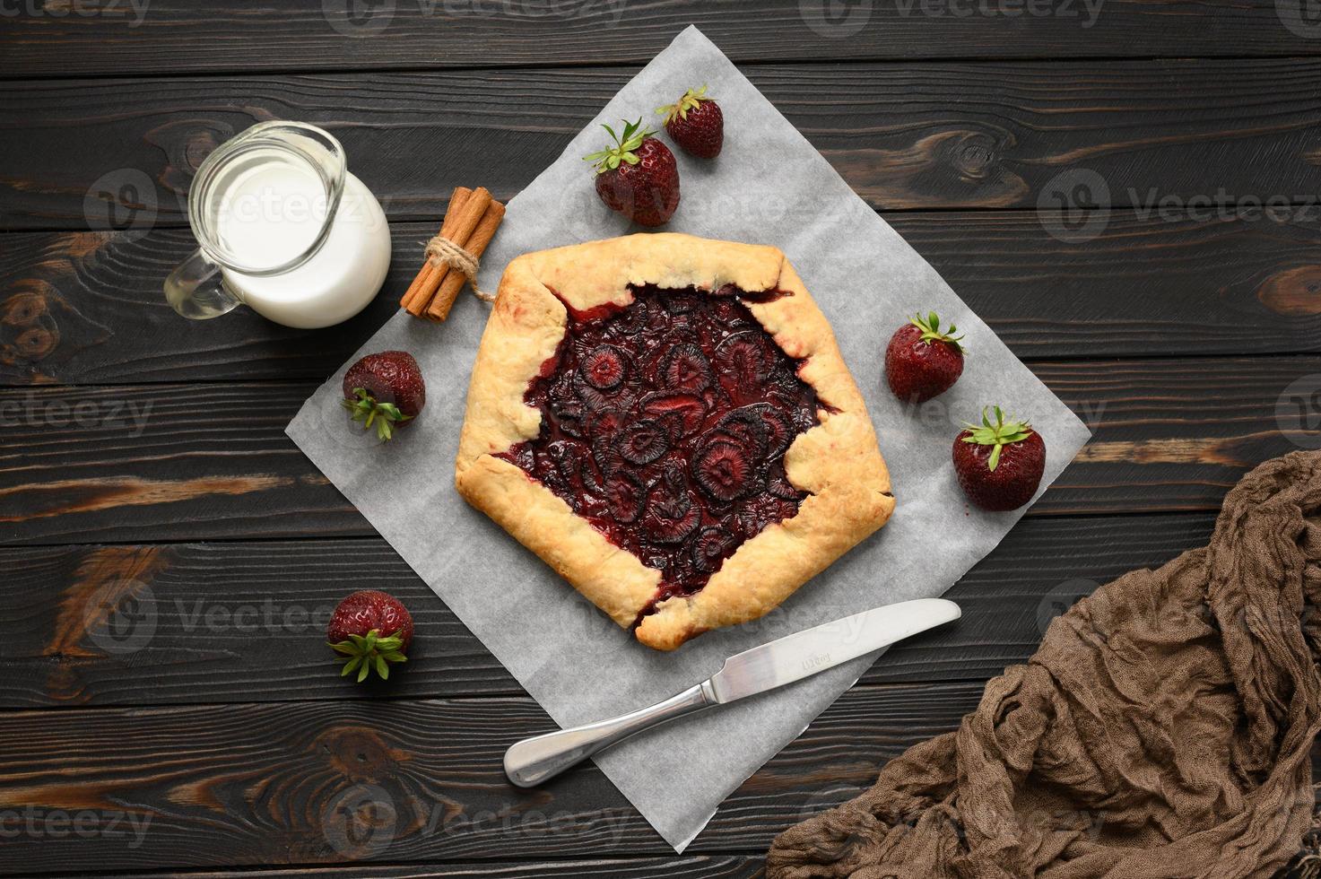 Strawberry galette on dark wooden background. Homemade photo