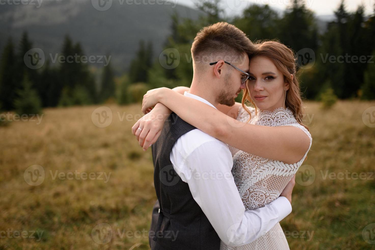 happy stylish bride and groom running and having fun in mountains on summer sunny day photo