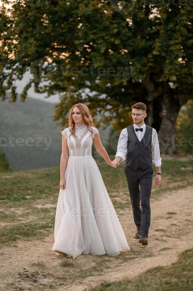 happy stylish bride and groom running and having fun in mountains on summer sunny day photo