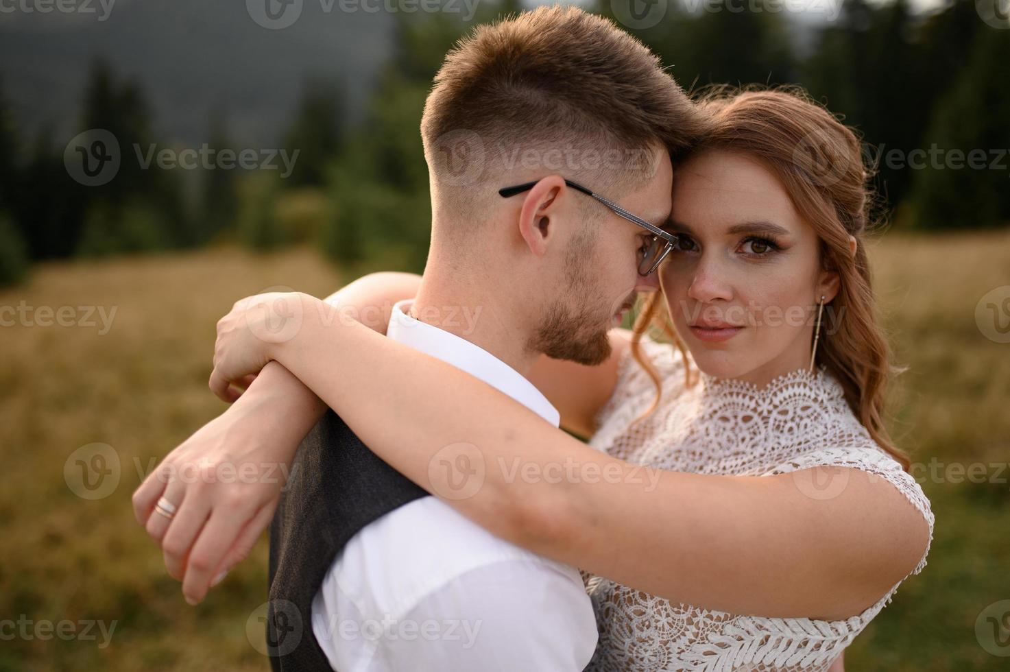 happy stylish bride and groom running and having fun in mountains on summer sunny day photo