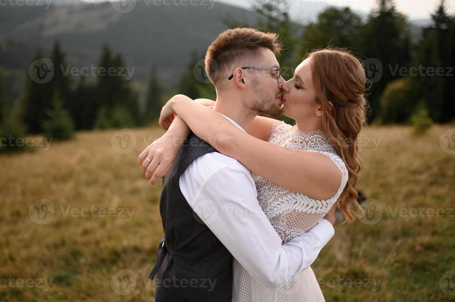 happy stylish bride and groom running and having fun in mountains on summer sunny day photo