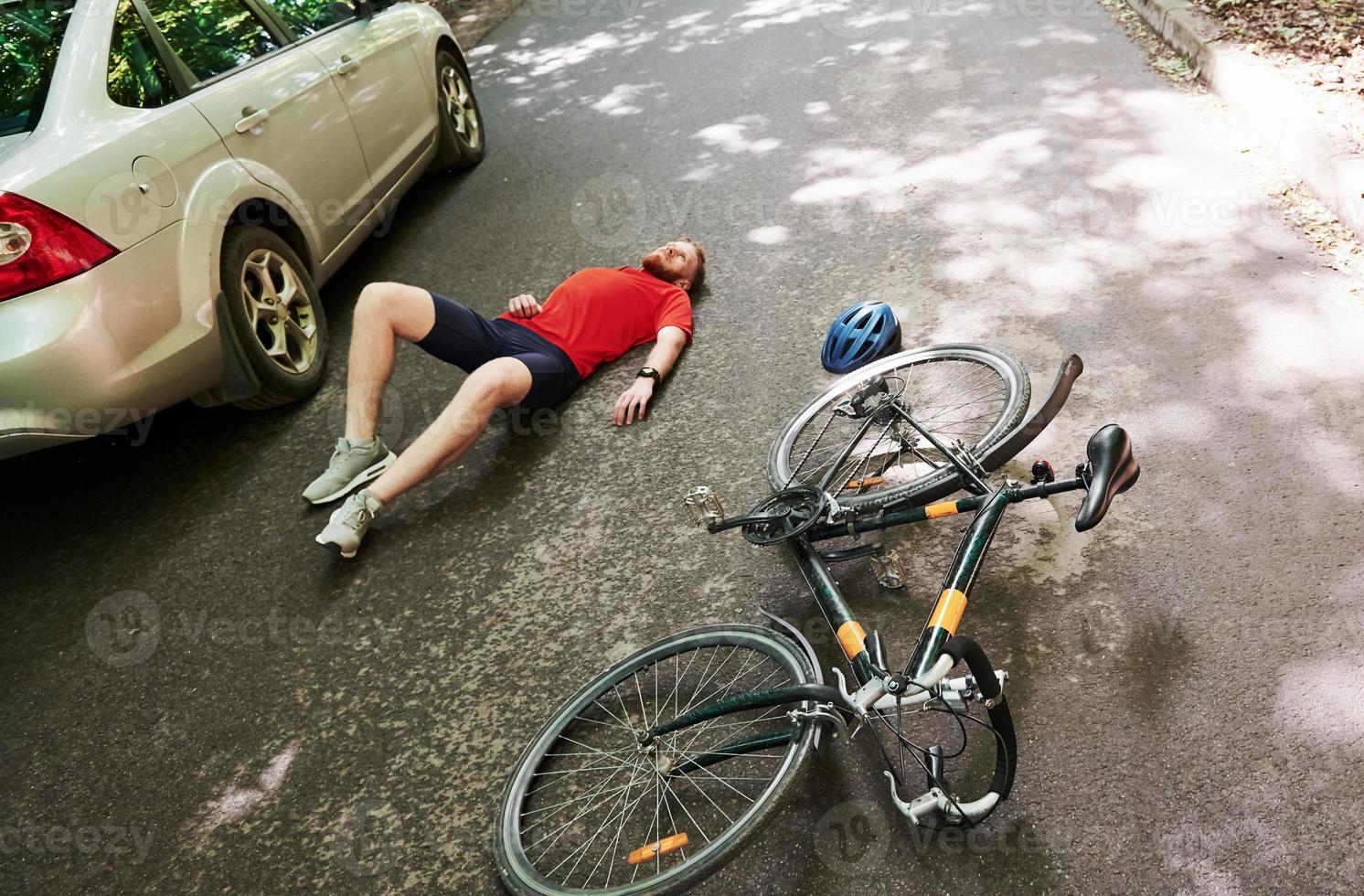 Aerial view. Victim on the asphalt. Bicycle and silver colored car accident on the road at forest at daytime photo