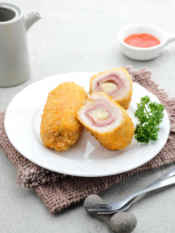 Crispy Cordon Blue, Chicken fillet roll with ham and cheese. Served in white plate on grey background. photo