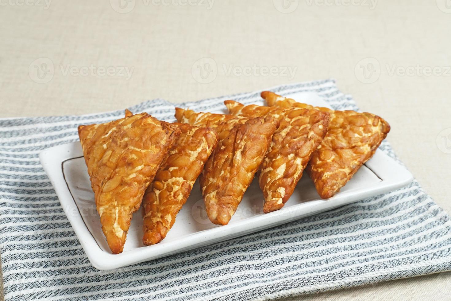 Tempeh, Tempe Goreng or Fried tempeh is Indonesia traditional food, made from fermented soybean seeds wrapped in banana leaves. Salty and savory, served as a side dish or snack photo