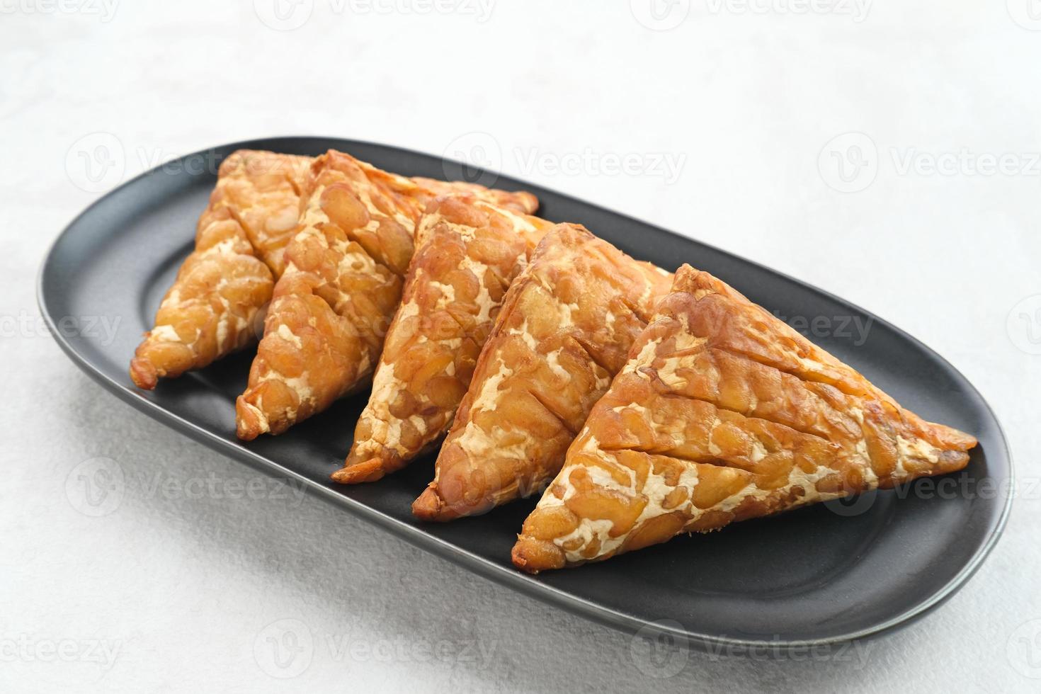 Tempeh, Tempe Goreng or Fried tempeh is Indonesia traditional food, made from fermented soybean seeds wrapped in banana leaves. Salty and savory, served as a side dish or snack photo