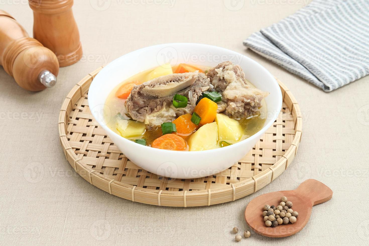 Sop Iga, Beef ribs soup, is Indonesian soup. Made from ribs, carrots, leeks, and potatoes. Served in white bowl. Selected focus photo