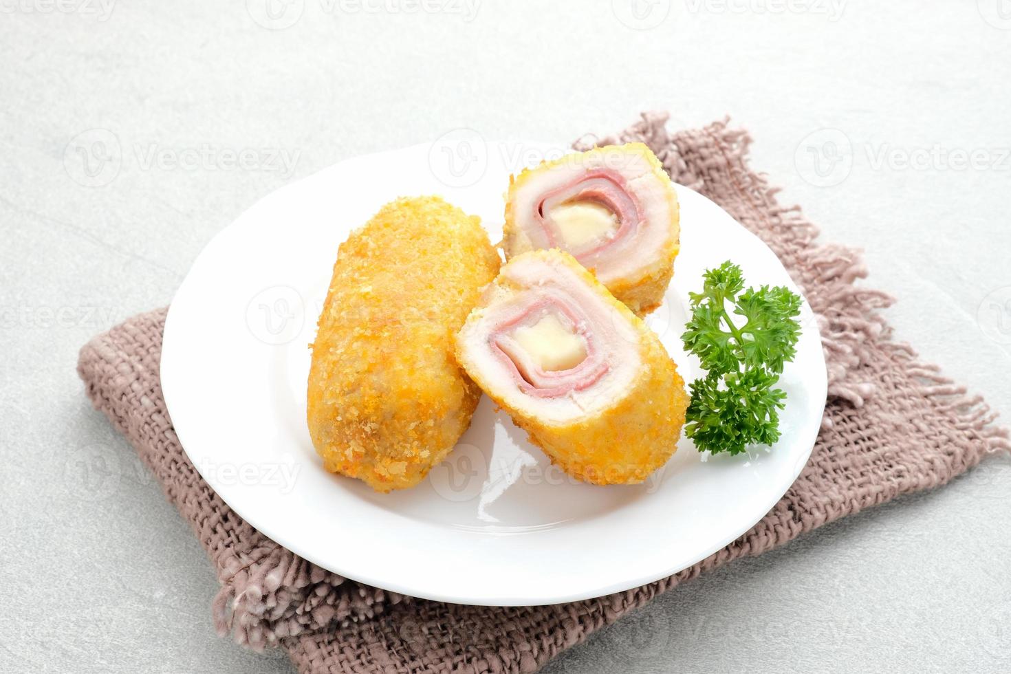 Crispy Cordon Blue, Chicken fillet roll with ham and cheese. Served in white plate on grey background. photo