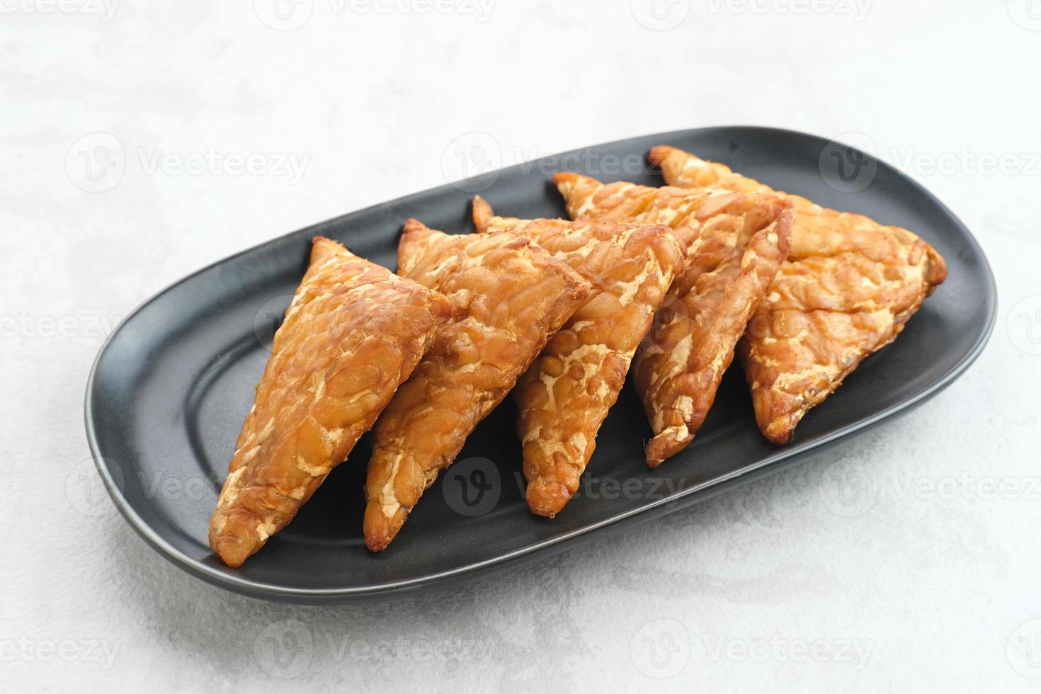 Tempeh, Tempe Goreng or Fried tempeh is Indonesia traditional food, made from fermented soybean seeds wrapped in banana leaves. Salty and savory, served as a side dish or snack photo