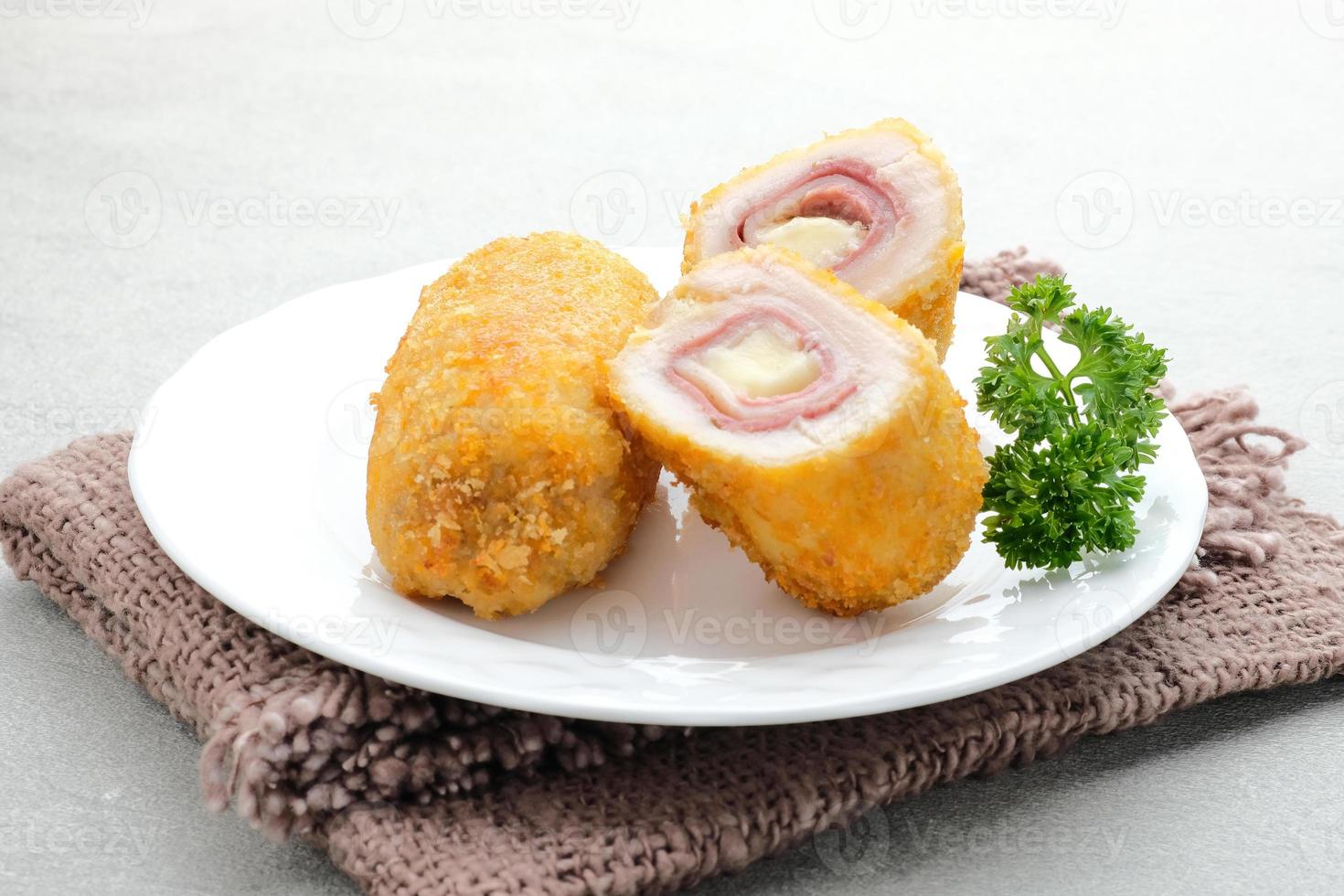 Crispy Cordon Blue, Chicken fillet roll with ham and cheese. Served in white plate on grey background. photo