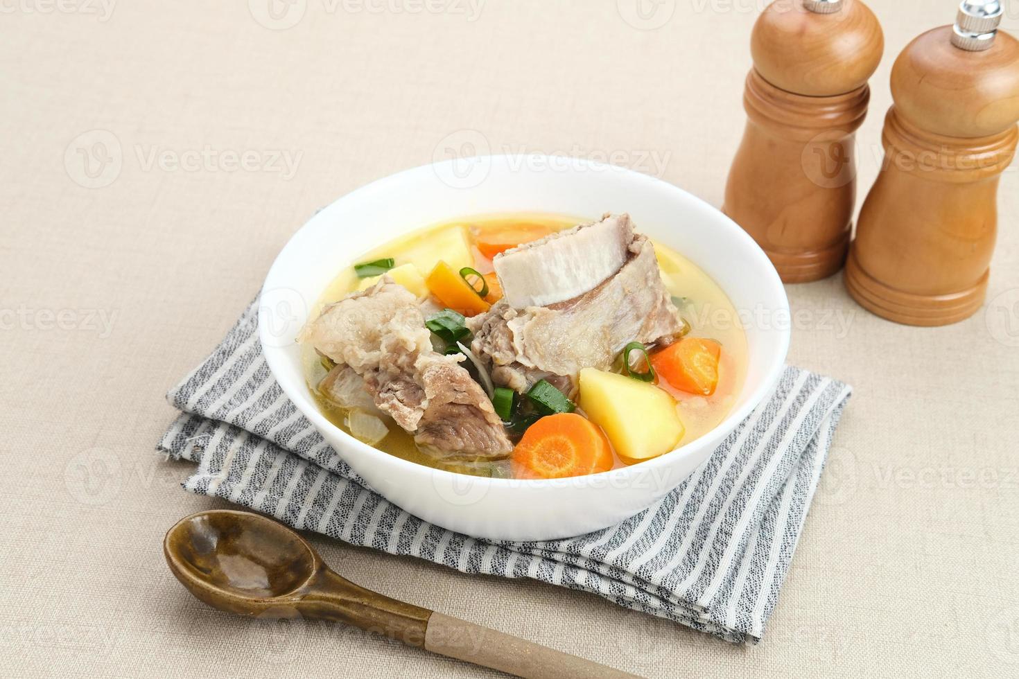 Sop Iga, Beef ribs soup, is Indonesian soup. Made from ribs, carrots, leeks, and potatoes. Served in white bowl. Selected focus photo