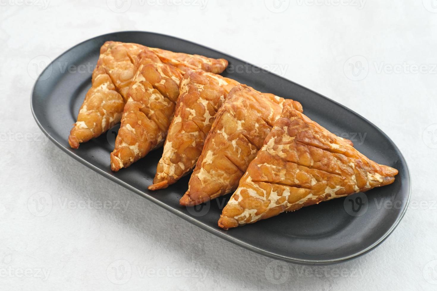 Tempeh, Tempe Goreng or Fried tempeh is Indonesia traditional food, made from fermented soybean seeds wrapped in banana leaves. Salty and savory, served as a side dish or snack photo