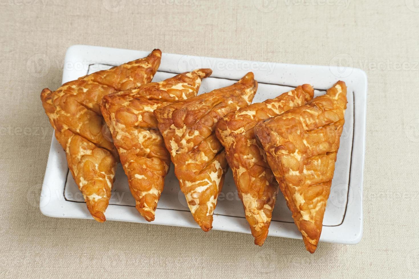 Tempeh, Tempe Goreng or Fried tempeh is Indonesia traditional food, made from fermented soybean seeds wrapped in banana leaves. Salty and savory, served as a side dish or snack photo